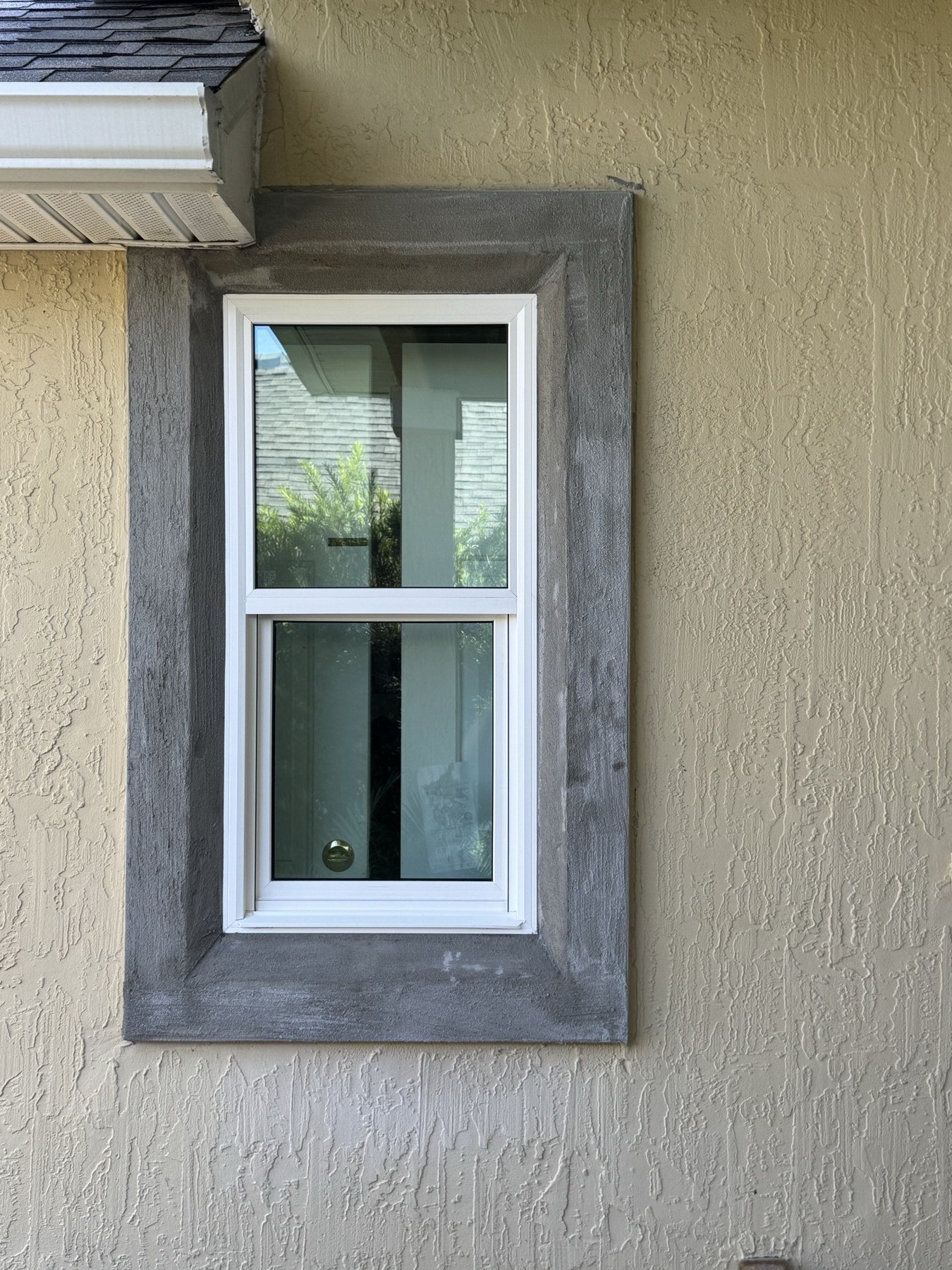 New impact window installed in stucco wall — gray frame finish